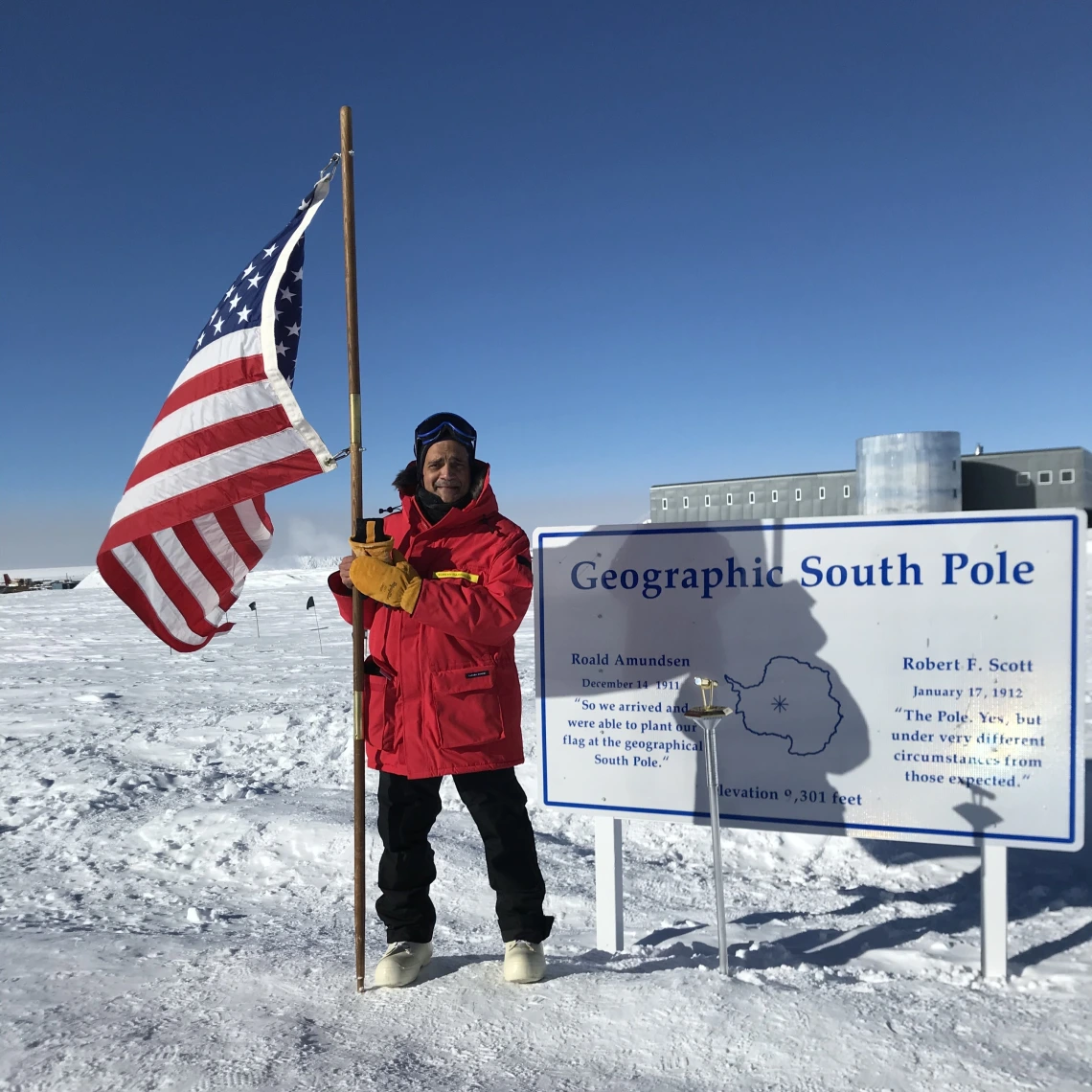 Suresh Garimella stands at the geographic south pole holding an American flag. 